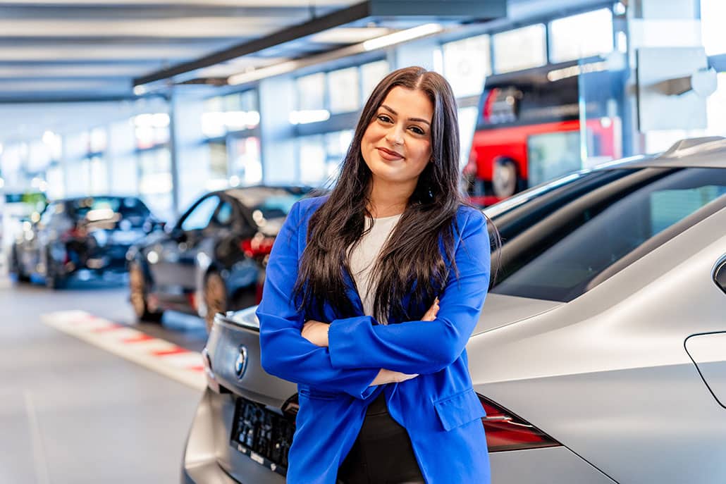Junge Frau in Autohaus Leebmann. BMW Fahrzeuge im Hintergrund zu sehen.