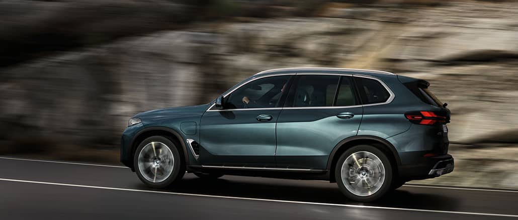 Dunkelblauer BMW X5 SUV fährt auf einer Straße mit Felswand im Hintergrund. Seitlich Fotografiert mit Überschrift: BMW PREMIUM SELECTION GARANTIE. DIE NEUEN GEBRAUCHTEN. Link blau hinterlegt: JETZT FAHRZEUG FINDEN.