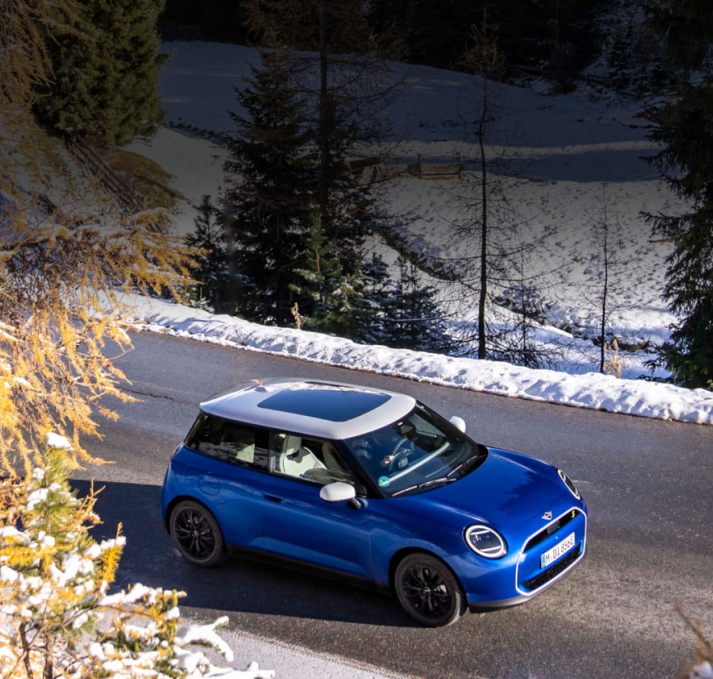 Eine blaue MINI Cooper SE auf winterliche Fahrbahn.